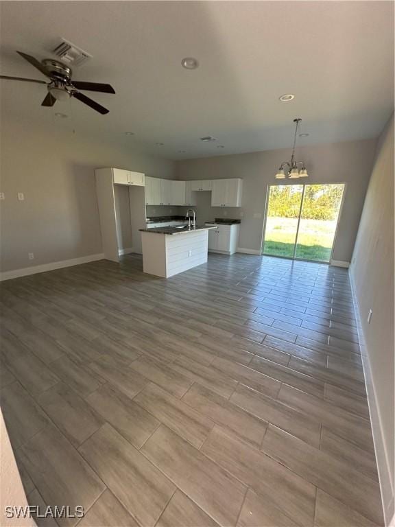 unfurnished living room featuring sink, light hardwood / wood-style floors, and ceiling fan with notable chandelier