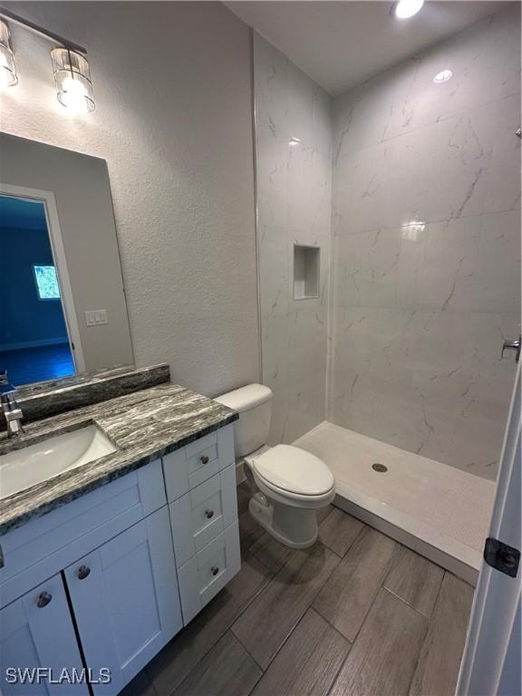 bathroom with tiled shower, vanity, and toilet