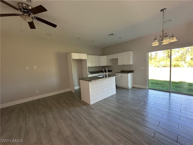 kitchen featuring white cabinets, light wood-type flooring, an island with sink, and hanging light fixtures