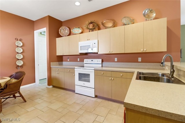 kitchen featuring light brown cabinetry, sink, and white appliances