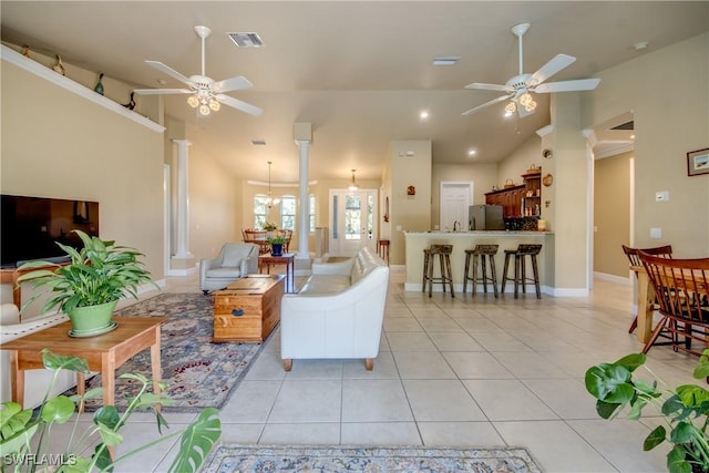 tiled living room featuring ornate columns, lofted ceiling, and ceiling fan with notable chandelier