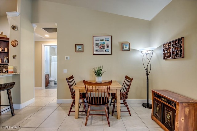 tiled dining space featuring ornamental molding and lofted ceiling