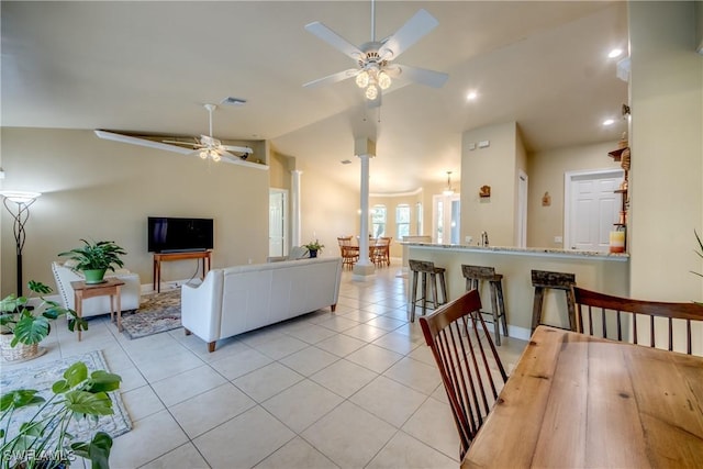 living room with ceiling fan with notable chandelier, vaulted ceiling, and light tile patterned flooring