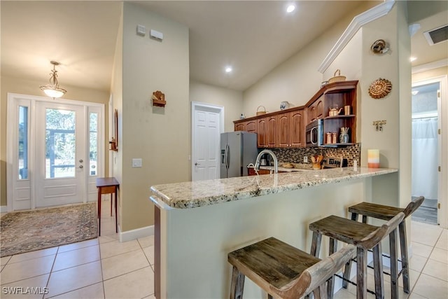 kitchen with a kitchen bar, kitchen peninsula, hanging light fixtures, and appliances with stainless steel finishes