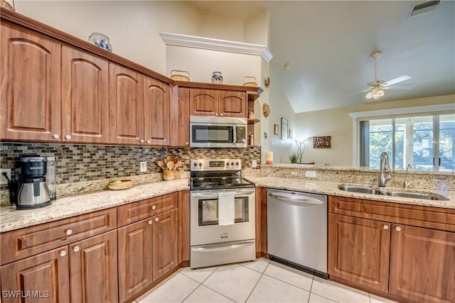 kitchen featuring light stone countertops, appliances with stainless steel finishes, ceiling fan, sink, and lofted ceiling