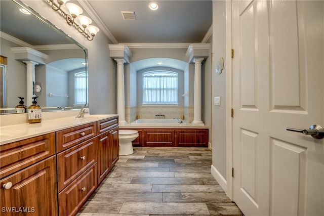 bathroom with hardwood / wood-style floors, vanity, ornamental molding, a tub to relax in, and decorative columns