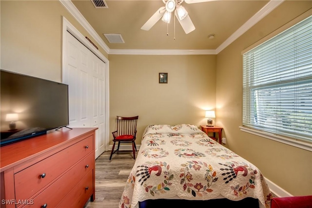 bedroom with light hardwood / wood-style flooring, crown molding, multiple windows, and a closet