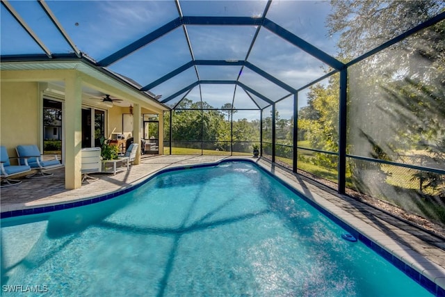 view of swimming pool with glass enclosure, ceiling fan, and a patio