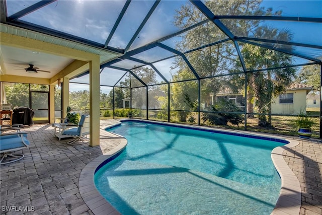 view of swimming pool featuring a patio area, ceiling fan, area for grilling, and glass enclosure