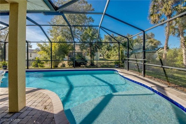 view of pool with glass enclosure and a patio