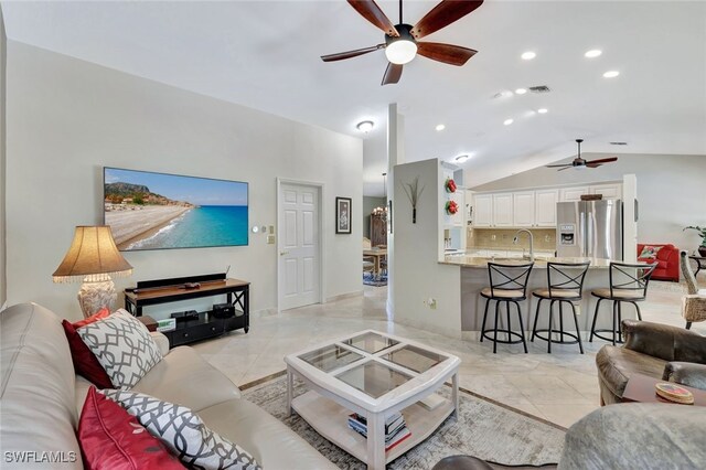 tiled living room featuring ceiling fan, sink, and vaulted ceiling