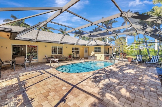 view of pool featuring glass enclosure, ceiling fan, and a patio