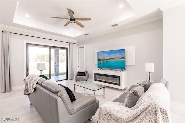 living room featuring light wood-type flooring, a tray ceiling, and ceiling fan