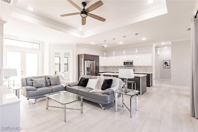 living room featuring french doors, crown molding, and a tray ceiling