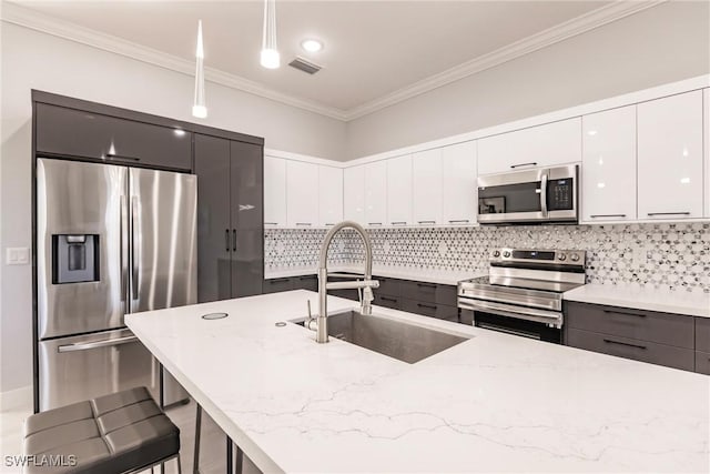 kitchen featuring hanging light fixtures, sink, appliances with stainless steel finishes, light stone counters, and a breakfast bar area