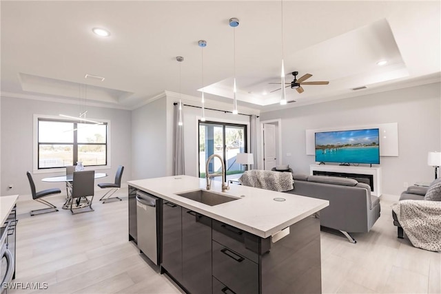 kitchen featuring a wealth of natural light, a tray ceiling, hanging light fixtures, and an island with sink