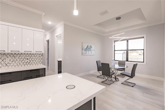 kitchen featuring pendant lighting, white cabinets, light stone countertops, and tasteful backsplash