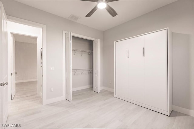 unfurnished bedroom with light wood-type flooring, two closets, and ceiling fan