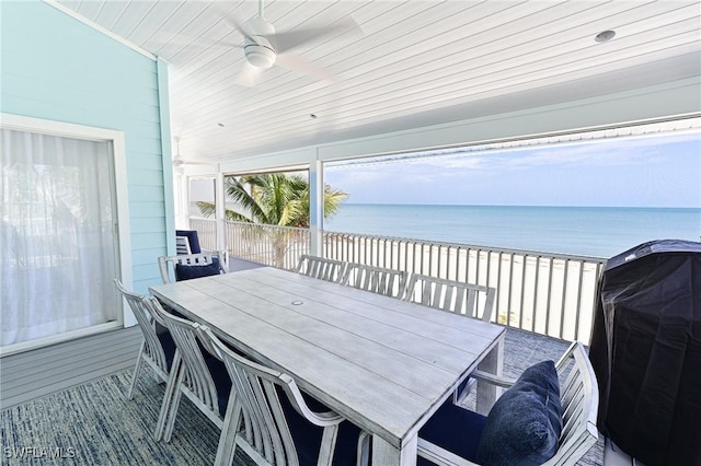 exterior space with ceiling fan, a water view, a beach view, and grilling area