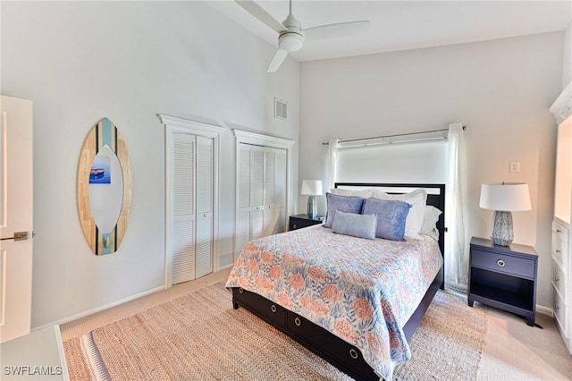 carpeted bedroom with multiple closets, ceiling fan, and high vaulted ceiling