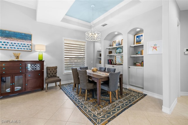 dining space featuring built in shelves, light tile patterned flooring, crown molding, and a tray ceiling