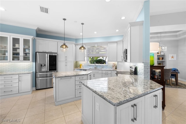 kitchen featuring a center island, stainless steel appliances, decorative light fixtures, white cabinets, and ornamental molding