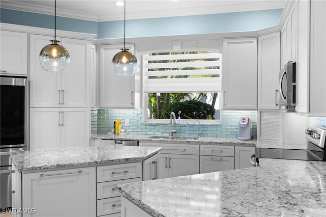 kitchen with decorative light fixtures, light stone counters, white cabinetry, and appliances with stainless steel finishes