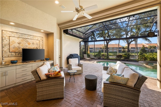 view of patio / terrace featuring area for grilling, outdoor lounge area, ceiling fan, sink, and a swimming pool with hot tub