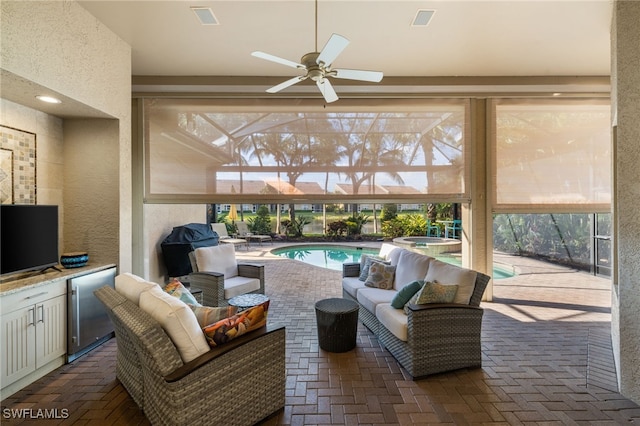 view of patio / terrace with an outdoor hangout area, an outdoor kitchen, a pool with hot tub, ceiling fan, and glass enclosure