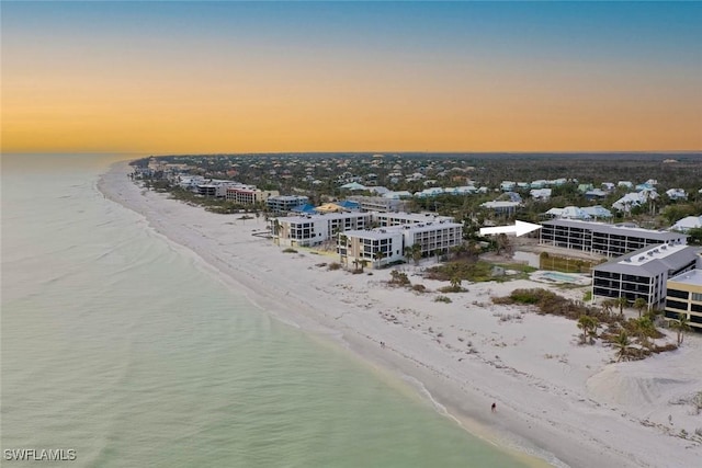 aerial view at dusk featuring a beach view and a water view