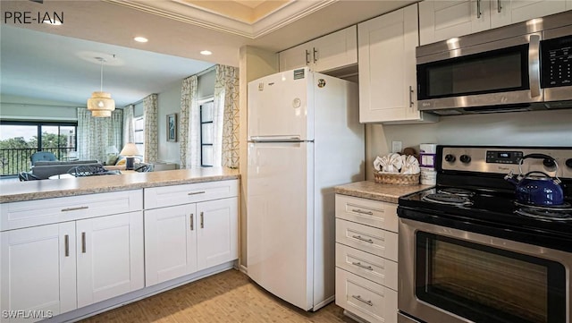 kitchen with white cabinets, appliances with stainless steel finishes, light wood-type flooring, and hanging light fixtures