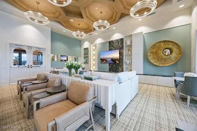 carpeted living room featuring french doors, a towering ceiling, coffered ceiling, and a chandelier