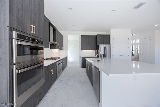 kitchen with an island with sink, appliances with stainless steel finishes, and sink