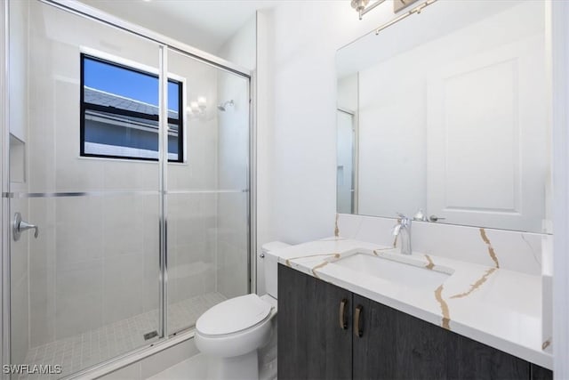 bathroom featuring vanity, walk in shower, and toilet