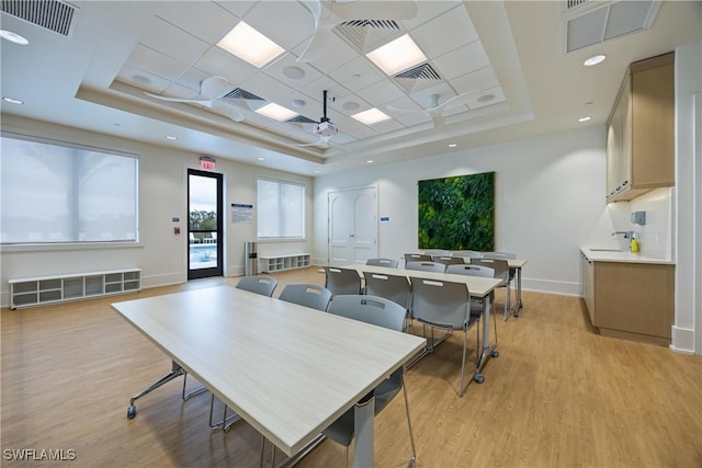 dining room featuring a paneled ceiling, light wood-type flooring, and a tray ceiling