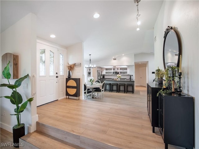 foyer featuring a chandelier, light hardwood / wood-style floors, and lofted ceiling