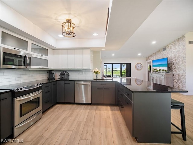 kitchen featuring gray cabinetry, a breakfast bar area, white cabinetry, kitchen peninsula, and stainless steel appliances