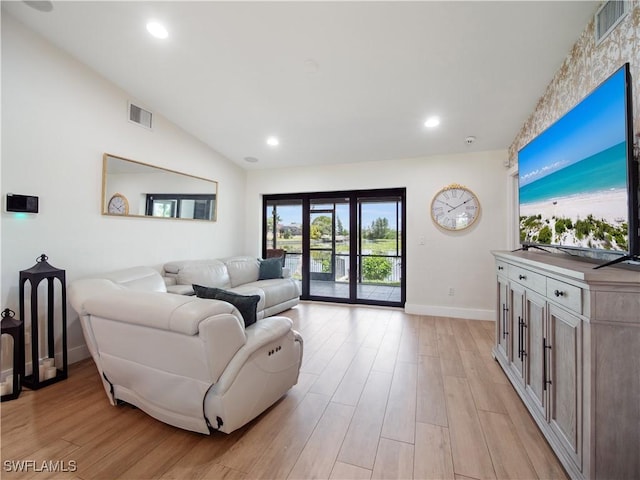 living room with french doors, light hardwood / wood-style floors, and lofted ceiling