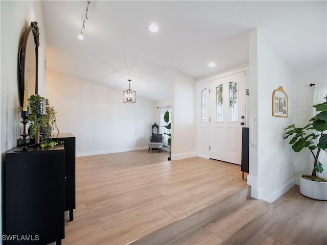 entrance foyer with a chandelier, light wood-type flooring, and track lighting