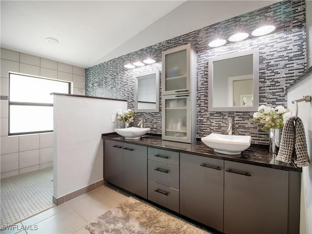 bathroom with tile patterned floors, decorative backsplash, lofted ceiling, and vanity