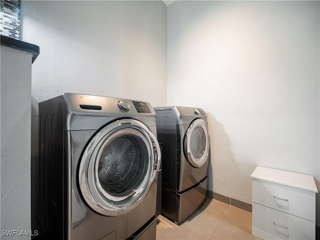 laundry area with separate washer and dryer and light tile patterned floors