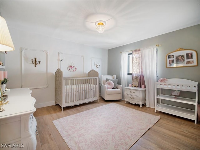 bedroom with wood-type flooring and a crib