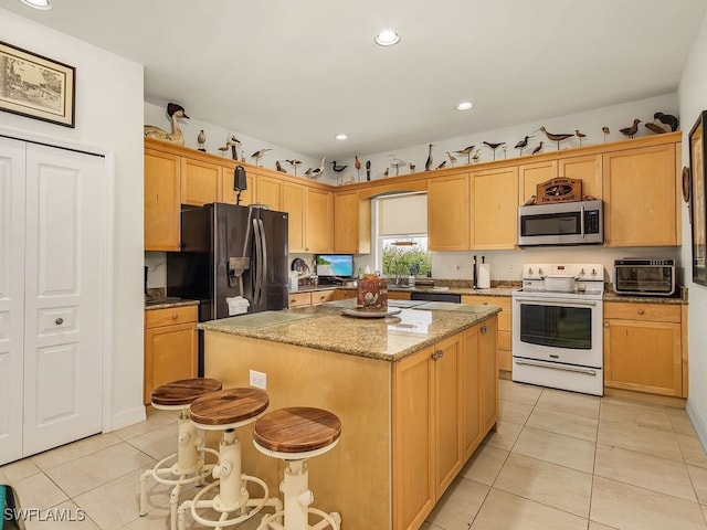 kitchen featuring light stone countertops, appliances with stainless steel finishes, a kitchen breakfast bar, a center island, and light tile patterned flooring