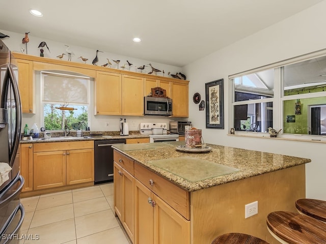 kitchen with light stone countertops, appliances with stainless steel finishes, sink, light tile patterned floors, and a kitchen island