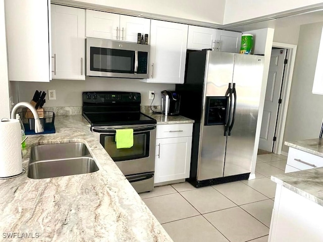 kitchen with light stone counters, stainless steel appliances, sink, light tile patterned floors, and white cabinets