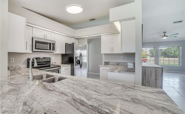 kitchen with light stone countertops, sink, white cabinets, and appliances with stainless steel finishes