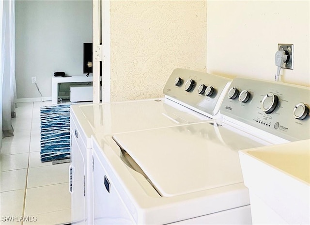 washroom with light tile patterned floors, sink, and washing machine and clothes dryer