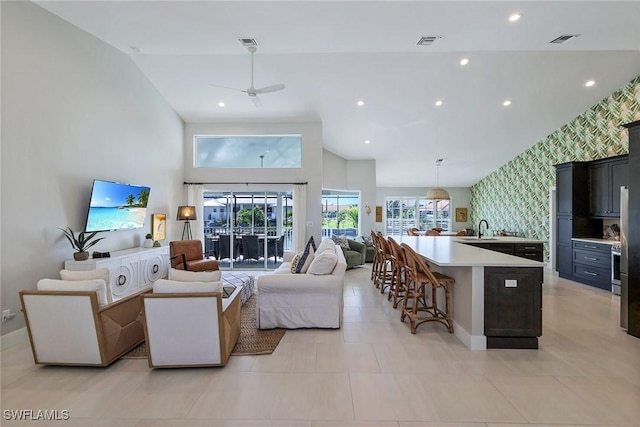 living room with ceiling fan, sink, light tile patterned floors, and lofted ceiling