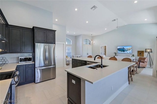 kitchen featuring sink, an island with sink, tasteful backsplash, a kitchen bar, and stainless steel appliances