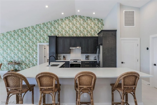 kitchen featuring a kitchen breakfast bar, sink, vaulted ceiling, appliances with stainless steel finishes, and a large island